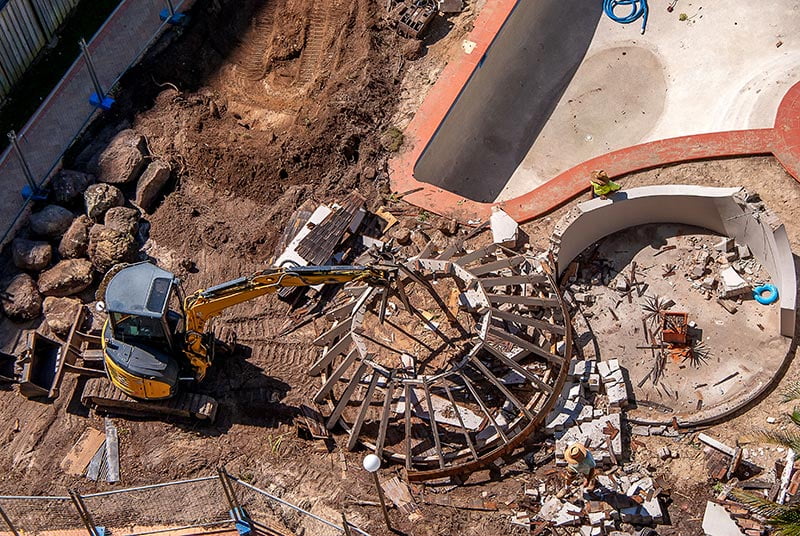 Excavator destroying an old swimming pool