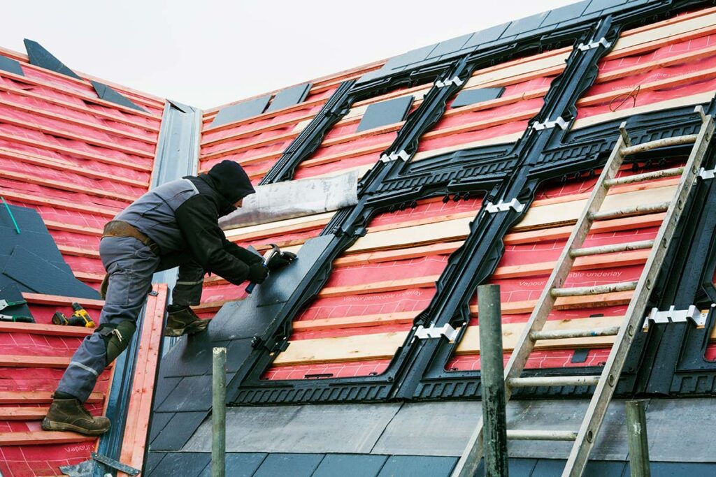 roofer replacing tiles on house roof