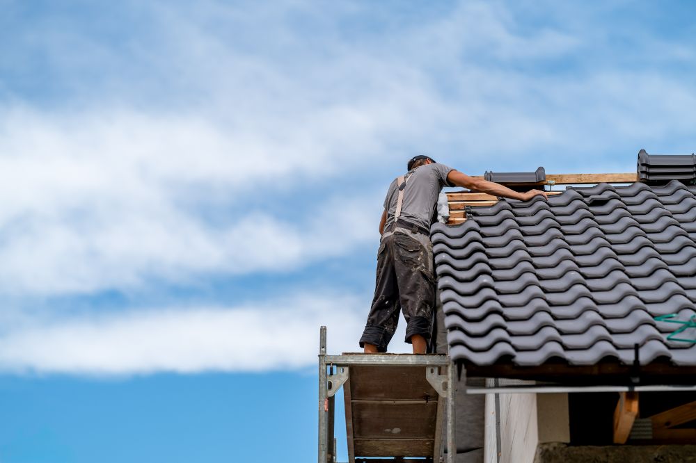 Roofer covering the tip of a roof thinking about insurance