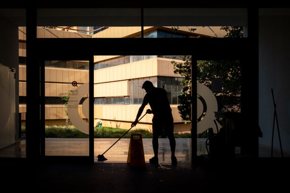 Man mopping outside building with wet floor sign to avoid costly lawsuits