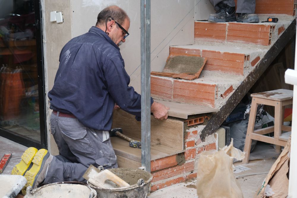 Male bricklayer laying bricks on stairs