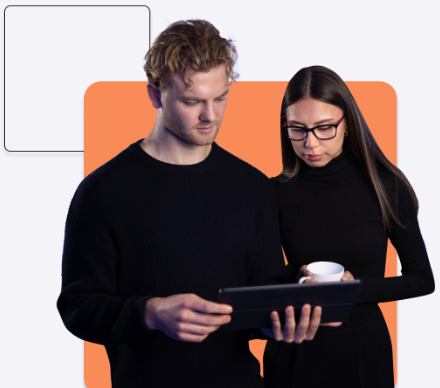 Two people are standing and looking at a tablet together. One holds the tablet, and the other holds a white cup. Both are dressed in black, potentially discussing cyber insurance strategies.