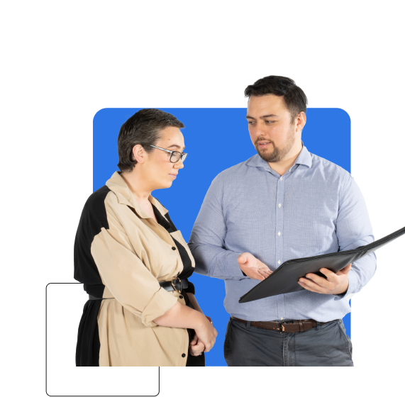 A man and woman are engaged in a discussion while looking at a black folder. The woman, who is a business insurance broker, is wearing glasses and a beige and black outfit, while the man is dressed in a light blue shirt.