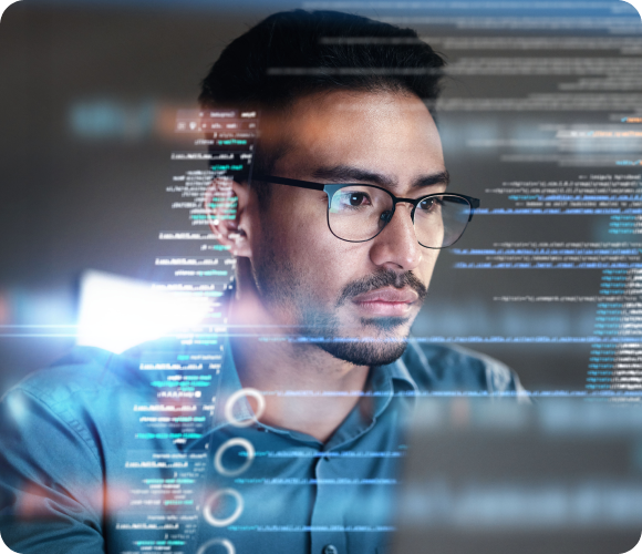 A man wearing glasses focuses intently on a computer screen with lines of code visible in the foreground, highlighted by a pop-up about cyber insurance.