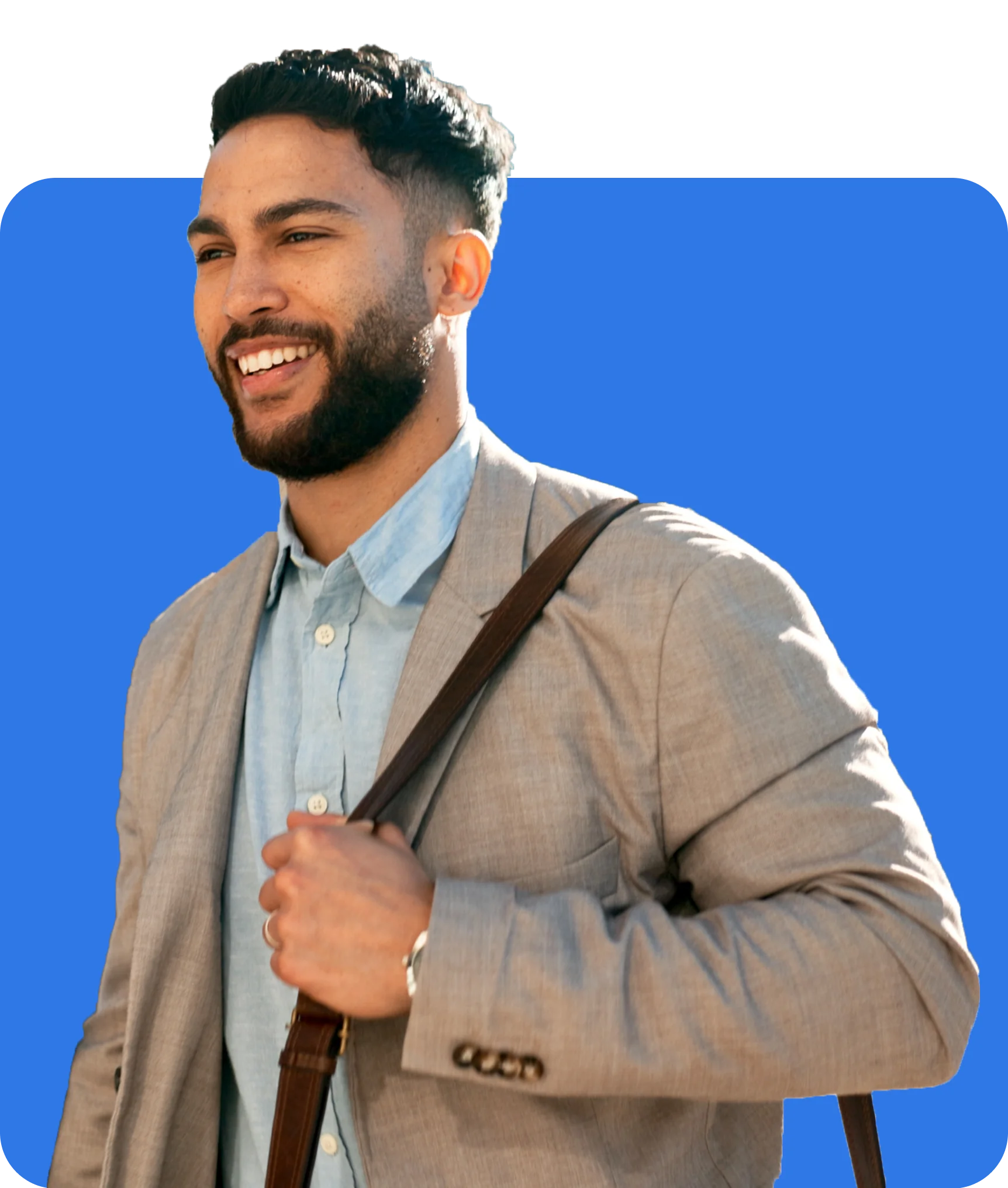 A man with a beard and short hair, wearing a light gray blazer over a light blue shirt, holding a brown shoulder bag, and smiling against a blue background, as he discusses the benefits of Commercial Property Insurance.