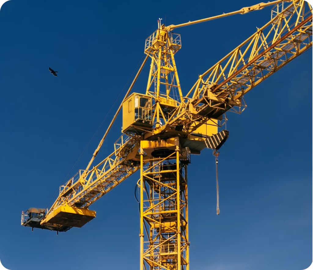 A yellow construction crane towers against a clear blue sky with a bird flying nearby, illustrating the importance of Plant and Equipment Insurance.