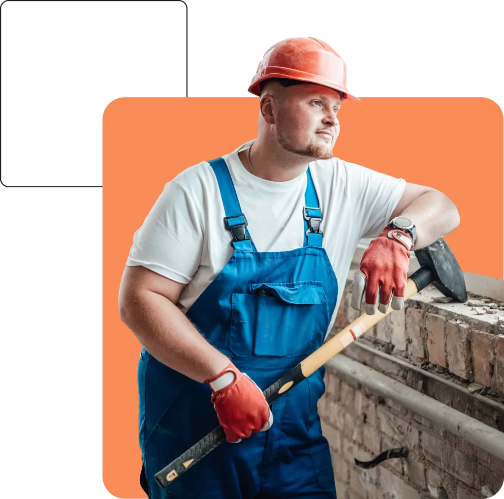 A construction worker in a red hard hat and blue overalls leans on a brick wall, holding a sledgehammer and looking to the side, seemingly contemplating the next steps, possibly of a demolition insured for safety.