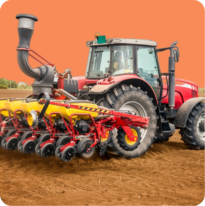 A red tractor with a yellow planter attachment is working on a field, preparing the soil under a clear, orange sky background.